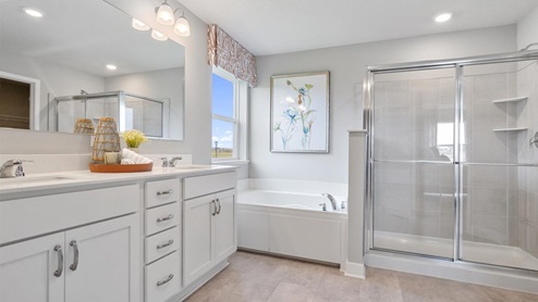 Private bathroom with white cabinets and separate shower and soaking tub.