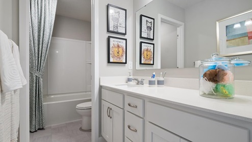Secondary bathroom with white cabinets and quartz vanity countertop.