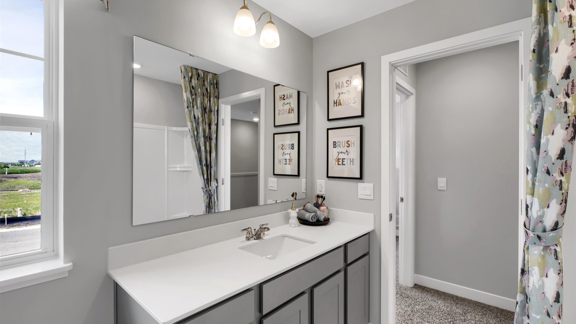 Private bathroom with gray cabinets and quartz vanity countertop.