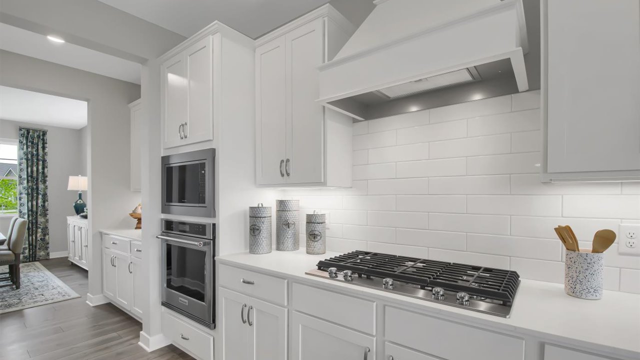 Gourmet kitchen with wood hood, gas cooktop and double ovens.