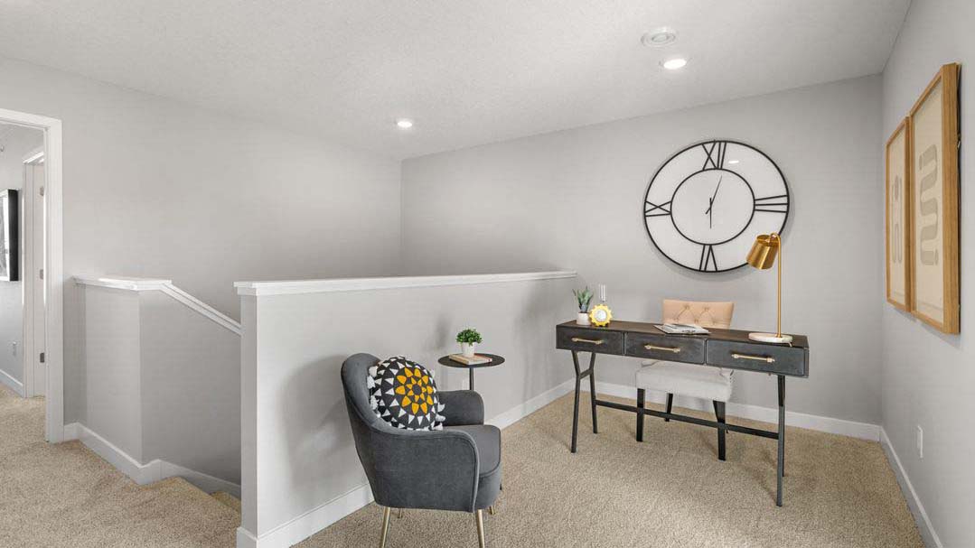 Upper level carpeted loft area staged with desk and armchair.