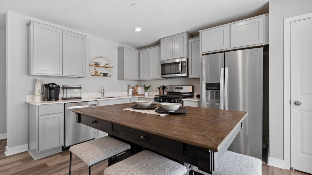 L-shaped kitchen with gray cabinetry and quartz countertops.