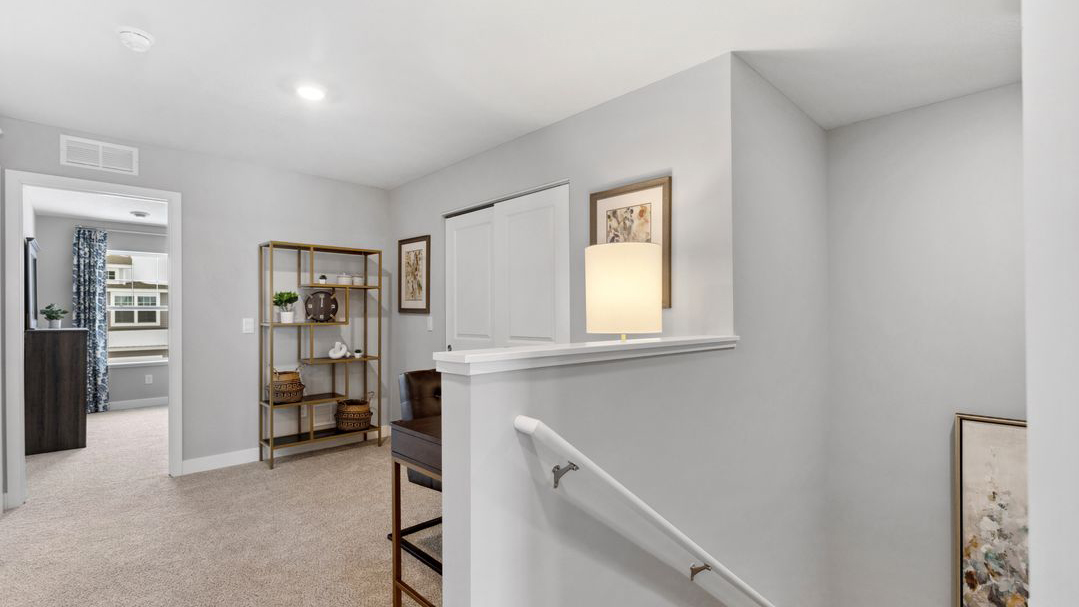 Upper level carpeted loft area staged with desk and armchair.