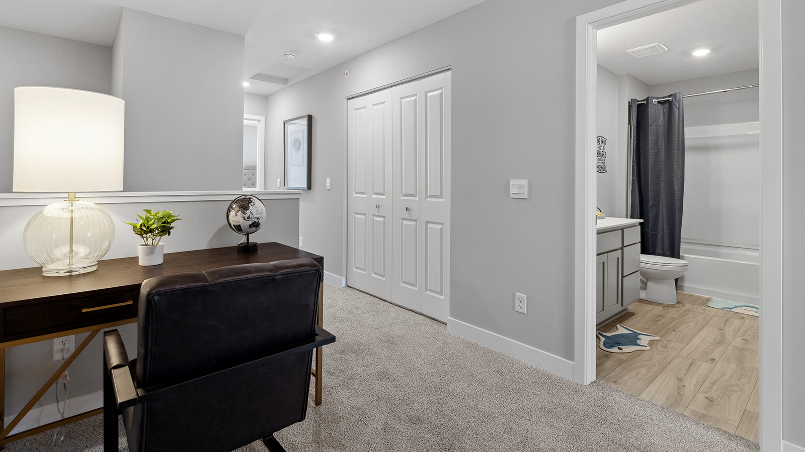 Upper level carpeted loft area staged with desk and armchair.