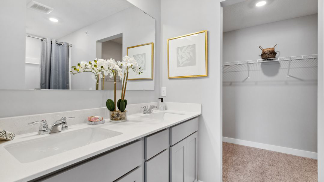 Bedroom suite's private bathroom with gray double sink vanity and quartz vanity countertops.