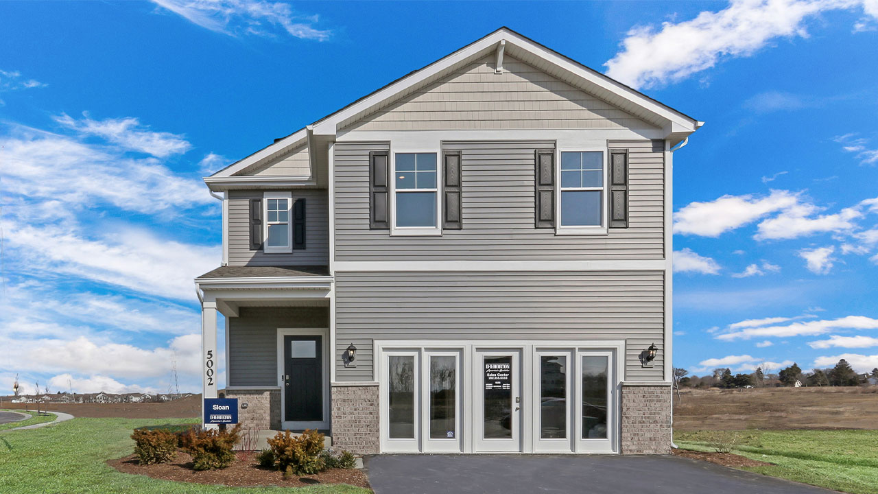two story model with grey vinyl siding and brick accents