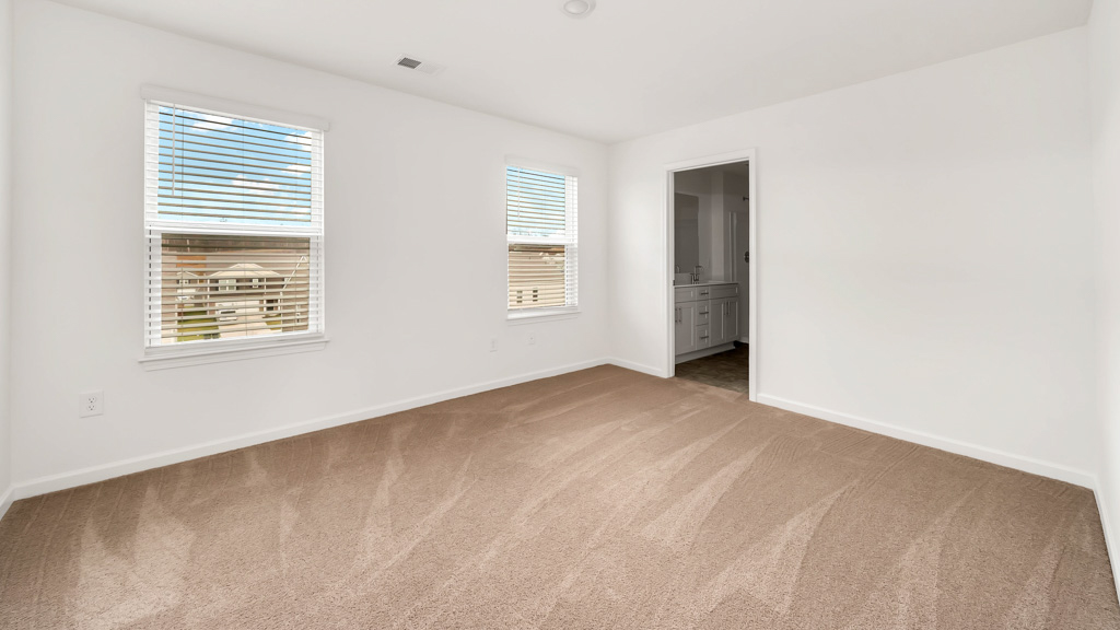 Primary bedroom with plush carpet floors and double light allowing windows
