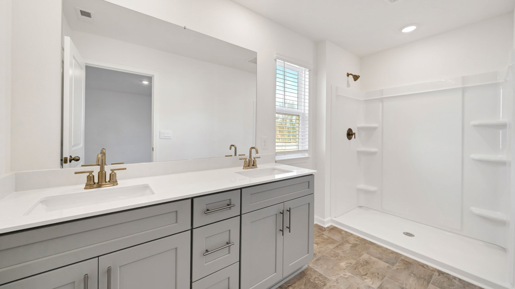 primary bathroom with double vanity and walk-in shower