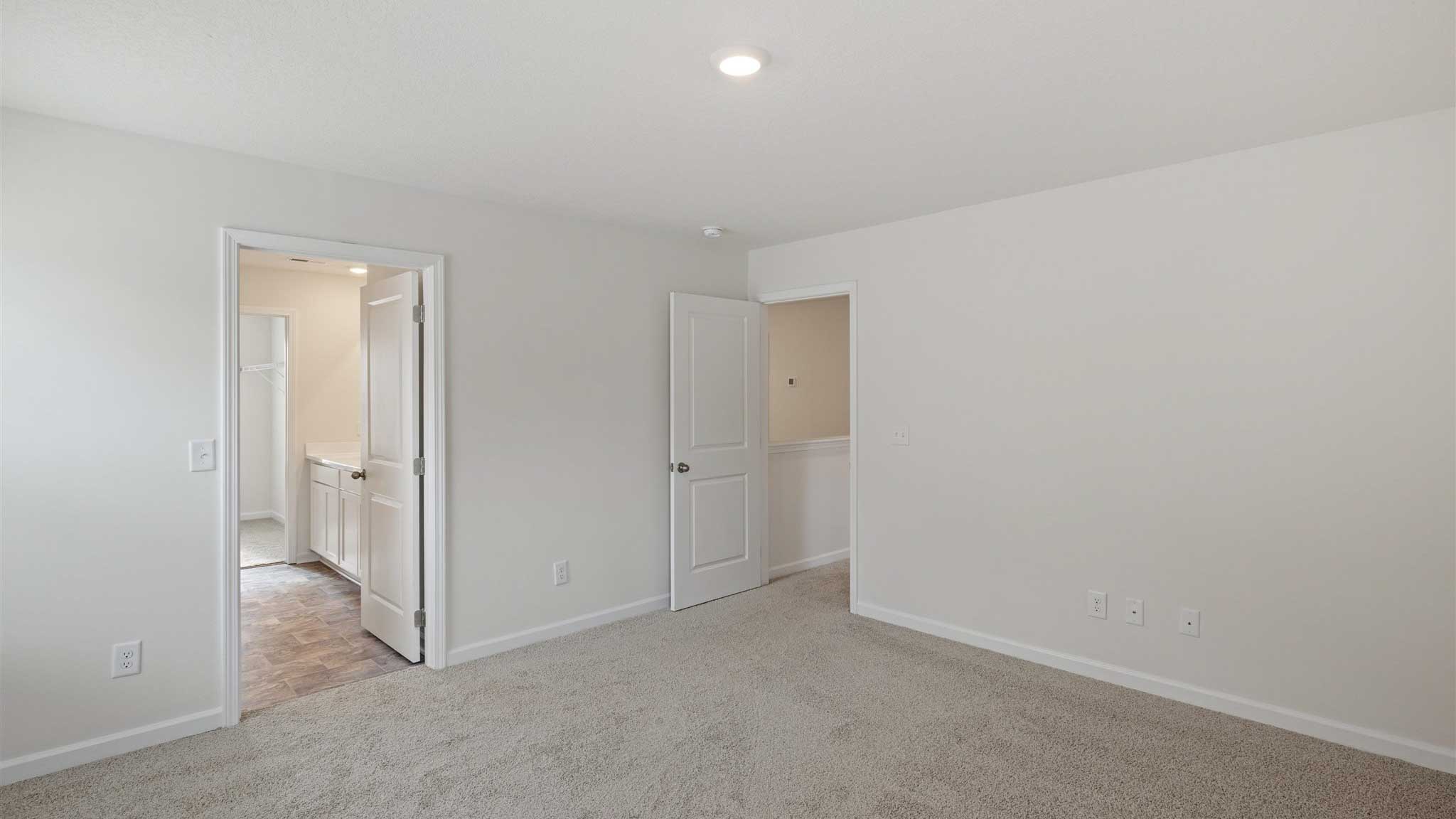 Bedroom with open door and white walls.