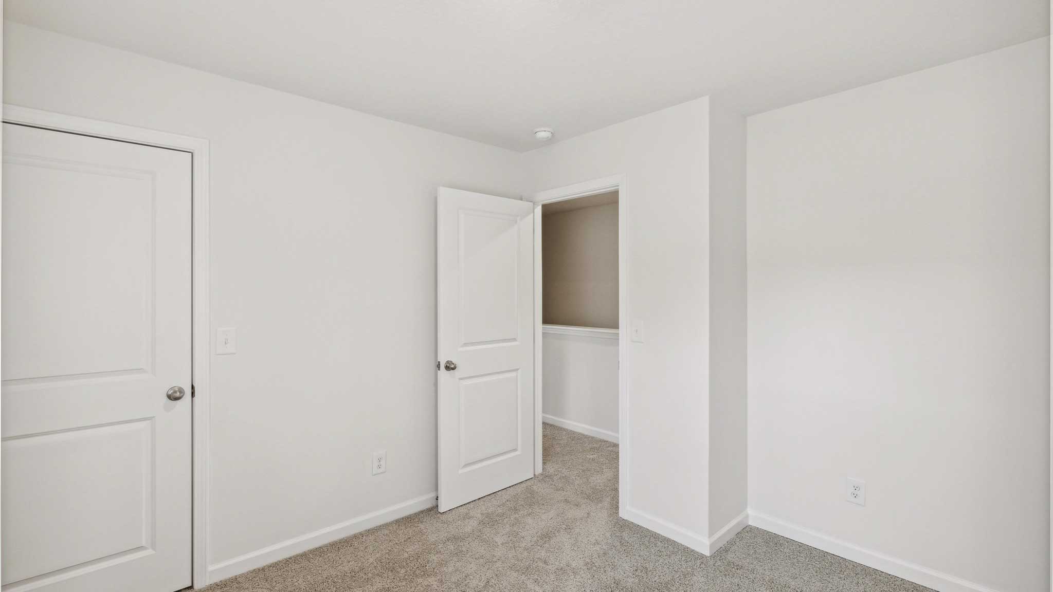 Bedroom with white walls and open door.