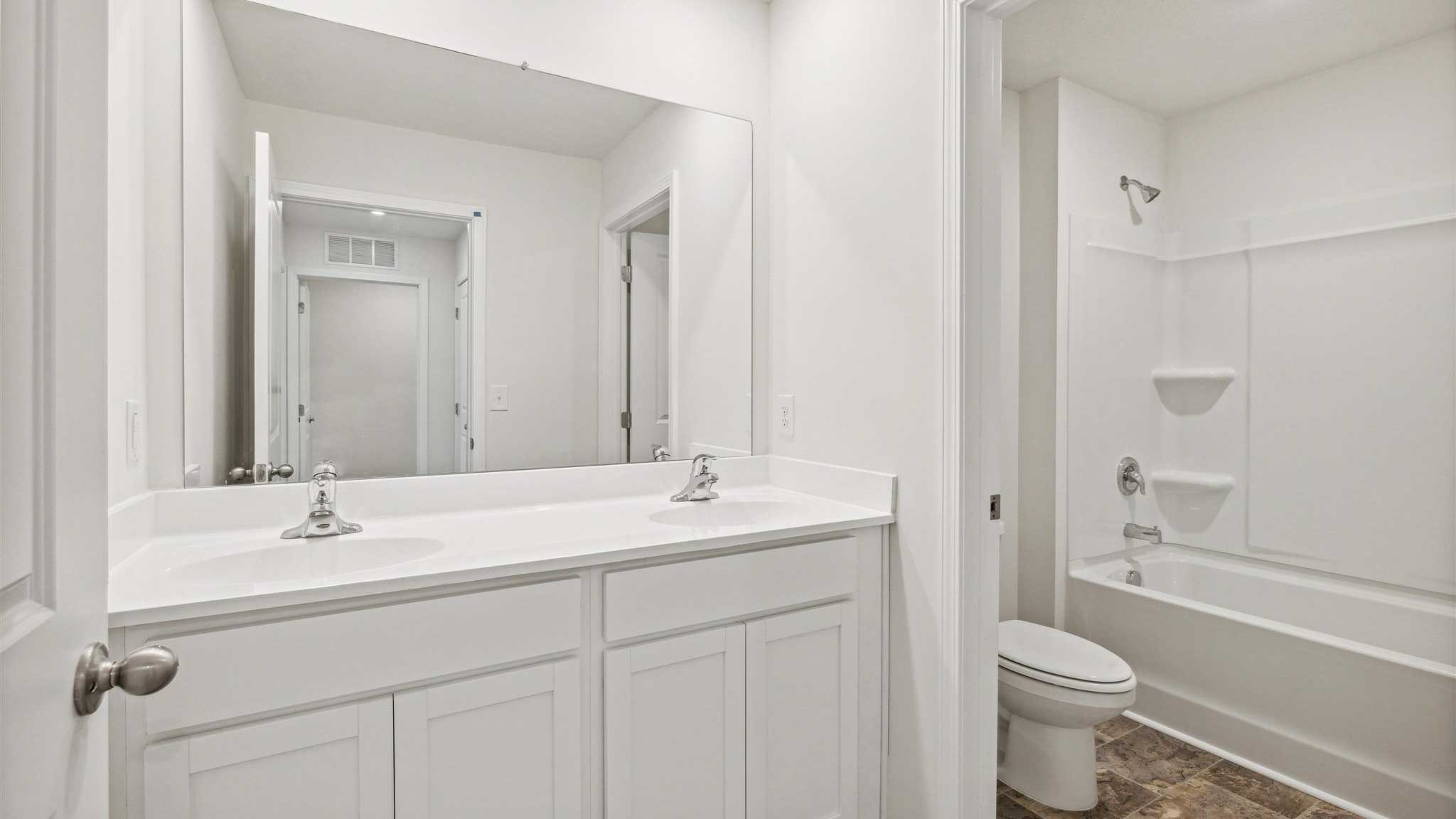 Bathroom with dual sinks and shower tub combo.