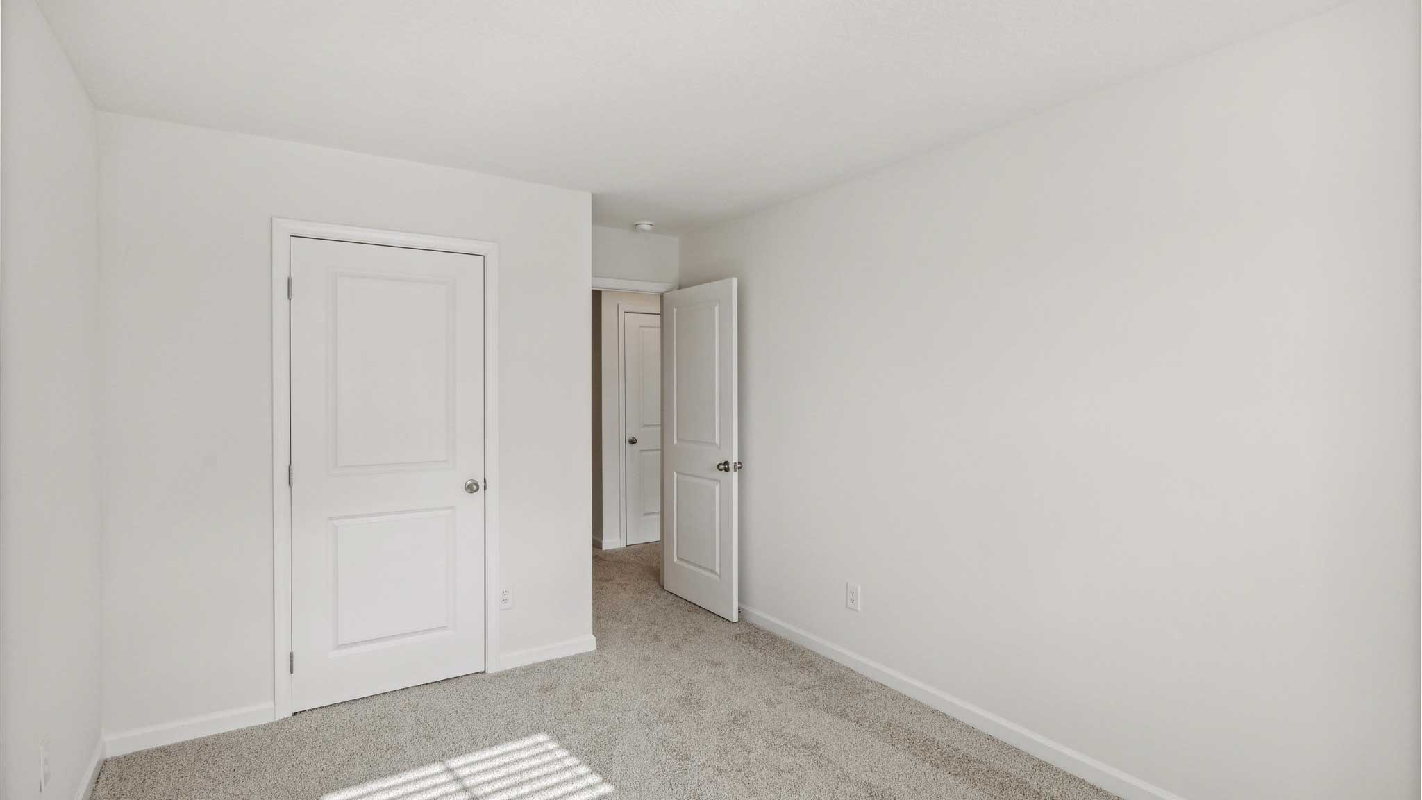 Bedroom with white walls and open closet.