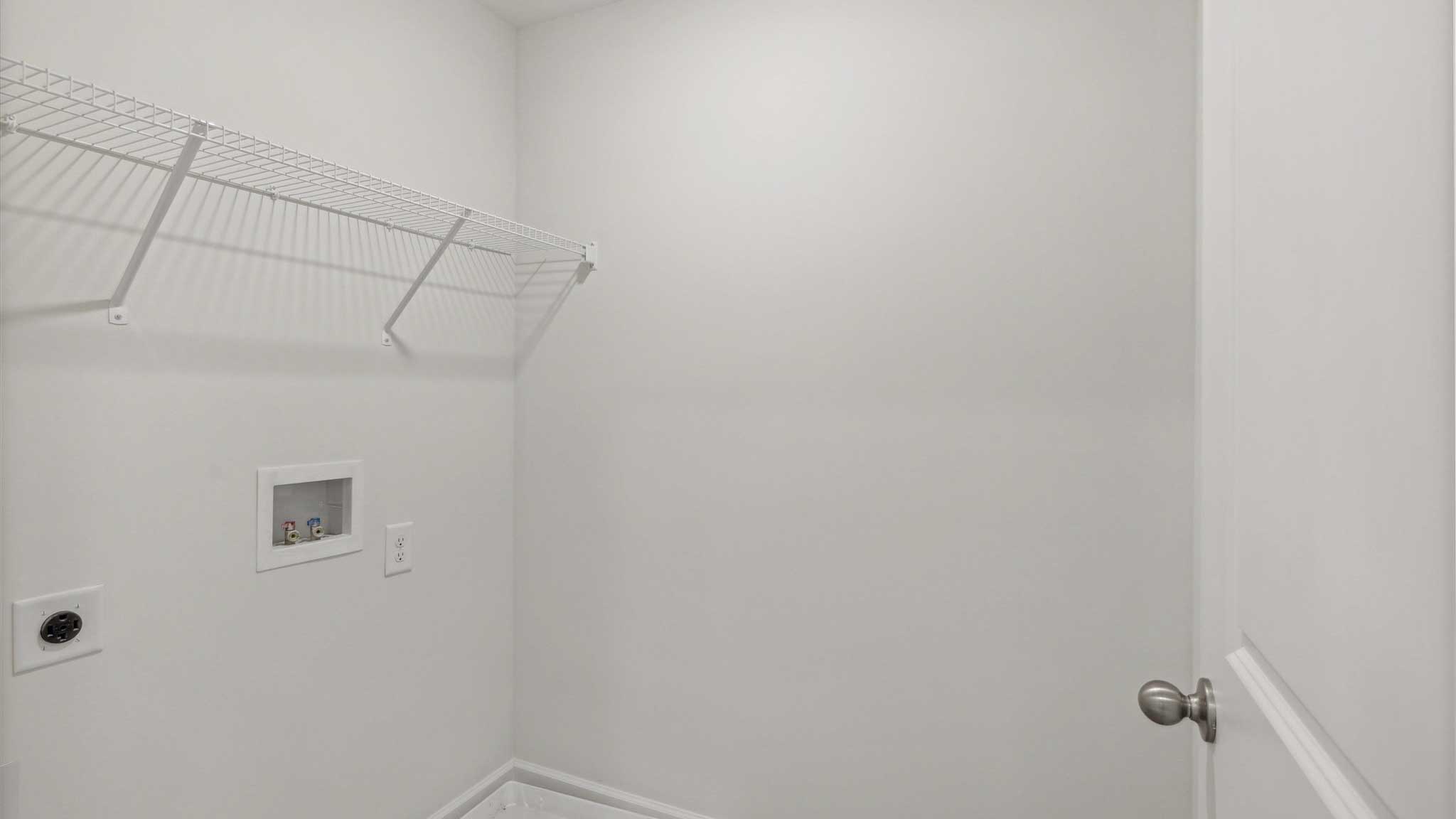 Laundry room has shelving and room for washer and dryer.