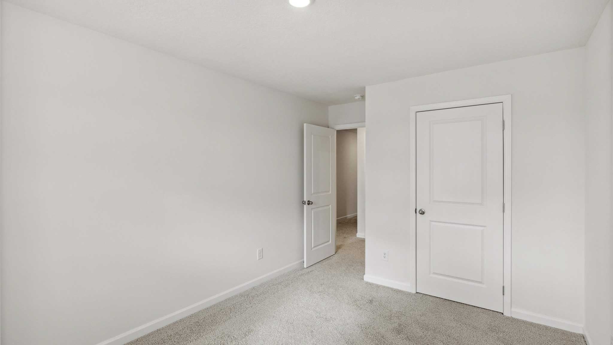 Bedroom with white walls and door.