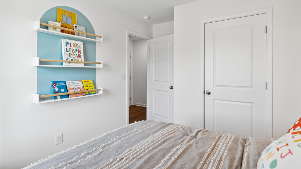 Bedroom with art on walls and bed from a back angle.