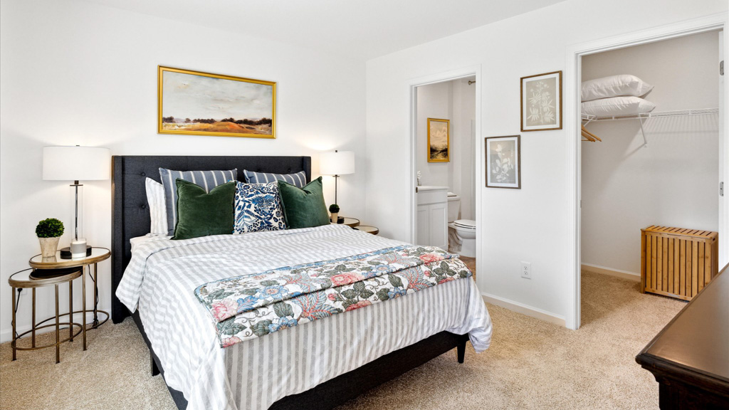 Bedroom with made bed and mirror above.