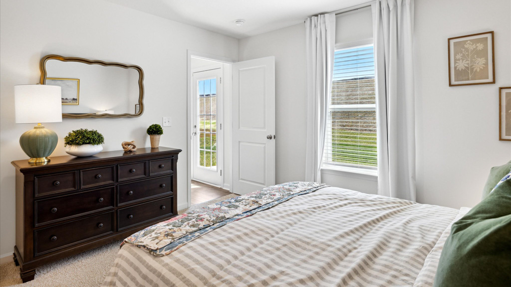 Bedroom with made bed and dresser.