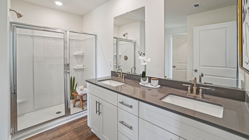 Interior primary bathroom with full size shower and two sinks