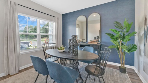 The breakfast area has large windows, table and blue wall.