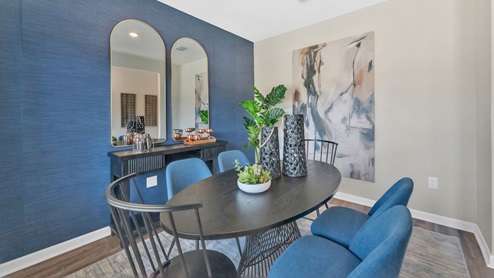 The blue accent wall of the breakfast area offsets the hardwood floors and round table.