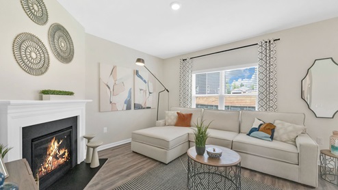 The living area has a couch, neutral walls, round art plates and hardwood floors.