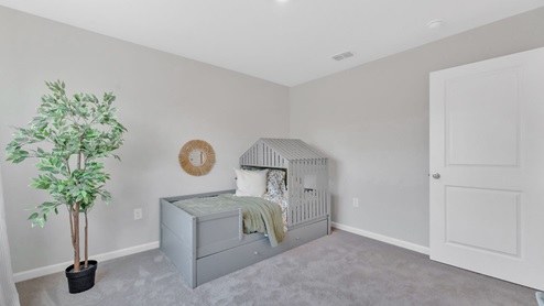 This bedroom has a white door, and furniture for a toddler or child including a bed.