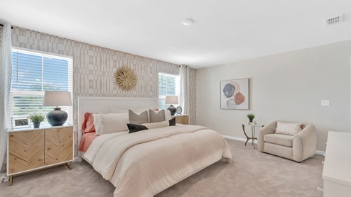 The primary bedroom has large windows, bedroom set with pink comforter and lots of natural light.