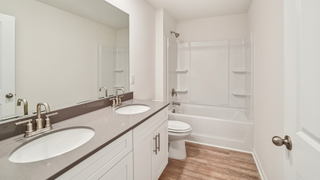 Bathroom with double vanity sink and step in shower.