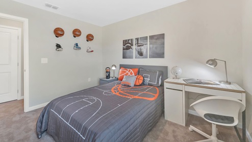 A secondary bedroom with bed, art and end table.