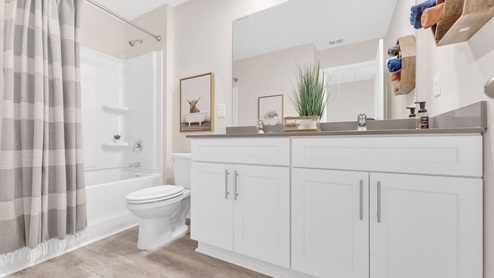 The secondary bathroom has white cabinets and standup shower.