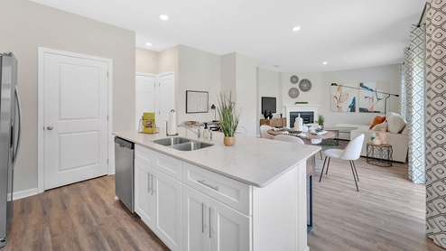 A modern kitchen featuring white cabinets, large island and elegant hardwood floors, creating an inviting atmosphere.