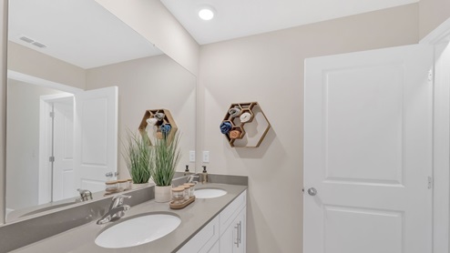 A view of the secondary bathroom sink with white door.