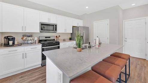 Another view of the kitchen featuring white cabinets, island and hardwood floors.