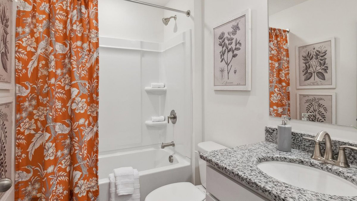 Family bathroom with stylish vanity, mirror, polished fixtures, cabinets, tub-shower combo in Saint Andrews Garth