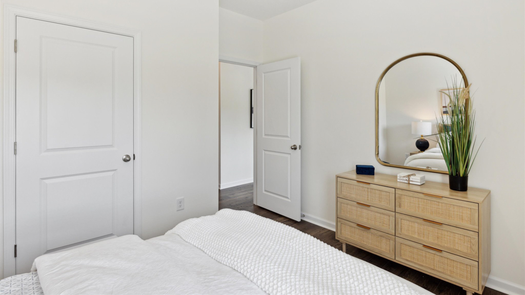 The bedroom has a dresser, mirror and bedding.