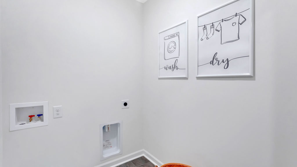 Laundry room with white walls, washer and dryer hookups, dark flooring, and two framed minimalist prints labeled “wash” and “dry” for a clean, modern look.