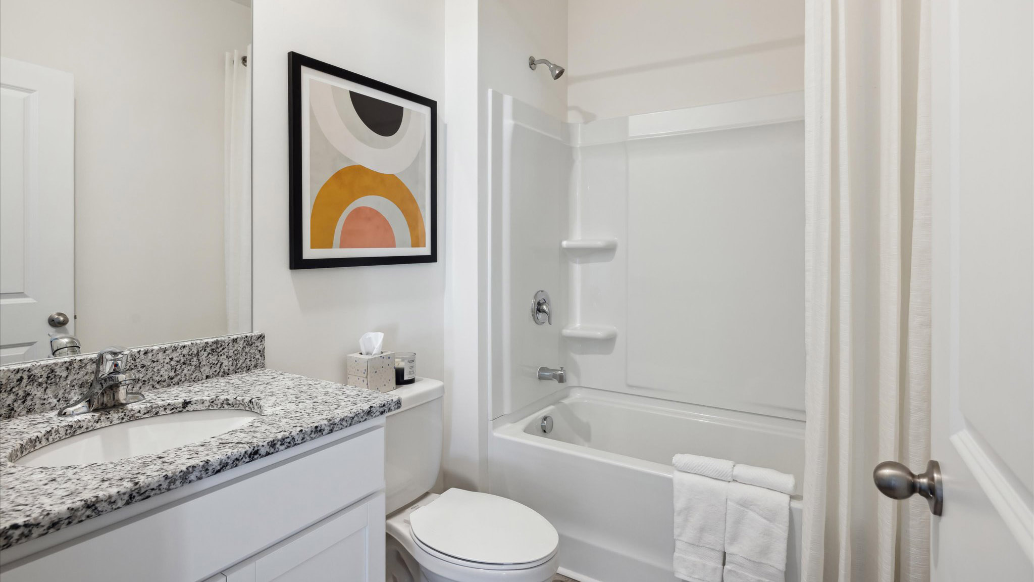 Family bathroom with stylish vanity, mirror, polished fixtures, cabinets, tub-shower combo in Saint Andrews Garth