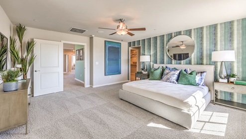 The Bedroom One Suite in our Spectrum Falls 2988 model with carpet flooring, ceiling fan with a light kit, a walk-in closet, and large windows.