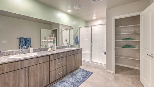 Attached to the Bedroom One Suite, our 2988 model bathroom with granite countertops at the double Bath Vanity, a walk-in shower, linen closet, mirror, and flat panel cabinets.