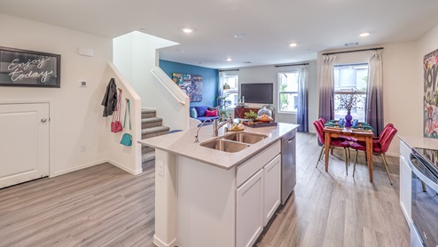 Our 1410 model kitchen in the Kalea Trails Community with white shaker cabinets, quartz countertops, a kitchen island/seating area, and Whirlpool Stainless Steel appliances.