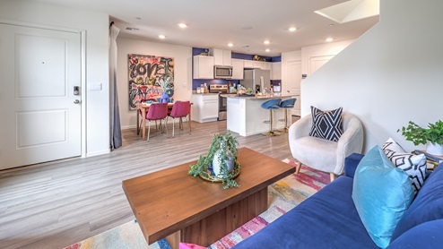 The Spectrum Trails 1410 Plan open concept Great Room with LVP panel flooring and a view of the kitchen.