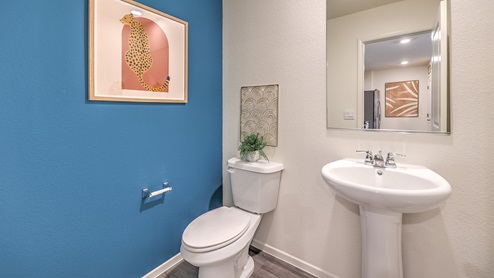 The powder bathroom in our Spectrum Trails 1309 model with a pedestal sink, mirror, and toilet.