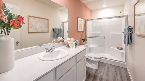 Attached to the Bedroom One Suite, our 1309 model bathroom with quartz/marble fusion countertops at the Bath Vanity, a walk-in shower, mirror, and white cabinets.
