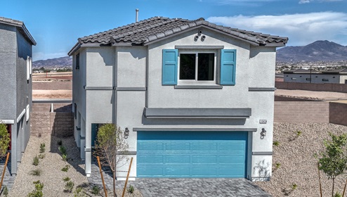Our 1865 model home in the Cambria Bay community with blue and grey exterior paint schemes, a flat tile roof, front yard landscaping, and paver walkways.