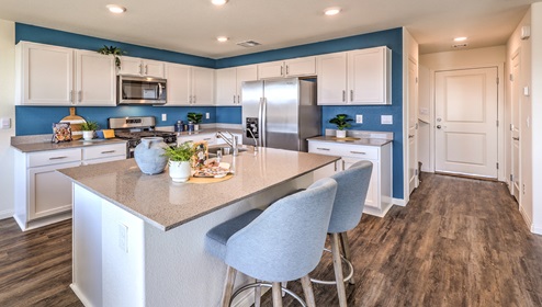 Our 1865 model kitchen in the Cambria Bay Community with grey shaker style cabinets, granite slab countertops, a kitchen island, large pantry, and Whirlpool Stainless Steel appliances.