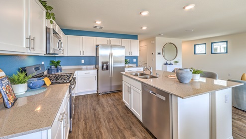 Our 1865 model kitchen in the Cambria Bay Community with grey shaker style cabinets, granite slab countertops, a kitchen island, large pantry, and Whirlpool Stainless Steel appliances.