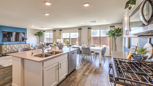 Our 1865 model kitchen in the Cambria Bay Community with grey shaker style cabinets, granite slab countertops, a kitchen island, large pantry, and Whirlpool Stainless Steel appliances.