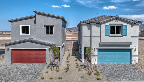 Our 1865 model home in the Cambria Bay community with blue and grey exterior paint schemes, a flat tile roof, front yard landscaping, and paver walkways.