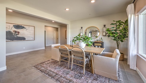 The Symmetry Manor 2754 model Dining Room adjacent to the kitchen and great room with a table and large window.