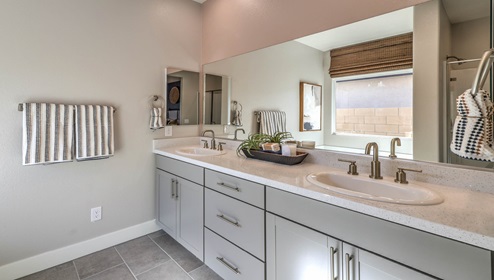 Attached to the Bedroom One Suite, our 2754 model bathroom with granite countertops at the double Bath Vanity, a walk-in shower, bath tub, mirror, and brown cabinets.
